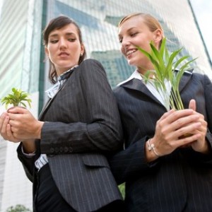 Two competitive businesswomen cupping their plants in their hands