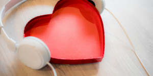 red paper heart surrounded by white headphones, suggesting listen to heart