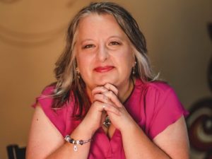 Christina Ammerman posed with her elbows on a table and her finger laced beneath her chin