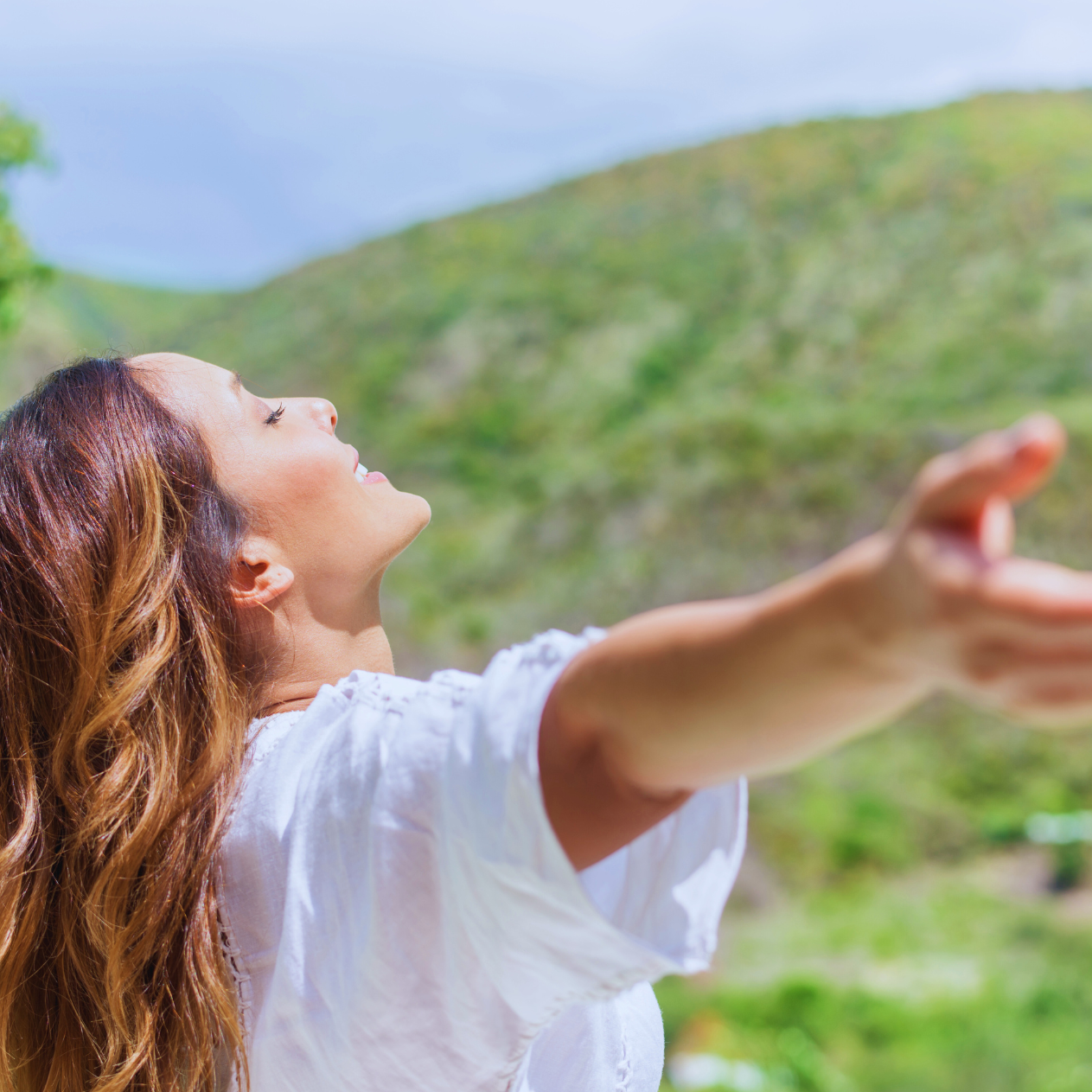stock photo of woman with head tilted toward the sky, arms outstretched to her sides