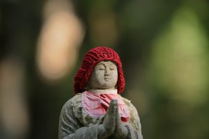 photo of a stone Buddha statue wearing a knitted hat and scarf