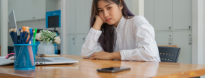 woman staring dejectedly at her phone sitting on the table